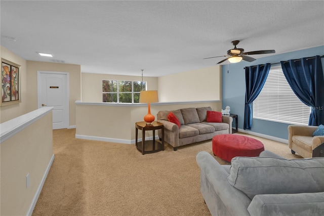 living room with ceiling fan, light colored carpet, and a textured ceiling