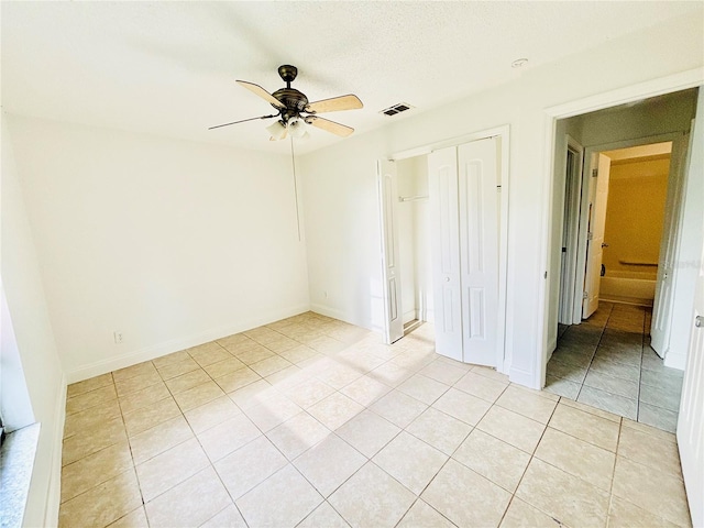 unfurnished bedroom featuring ceiling fan, light tile patterned flooring, and a closet