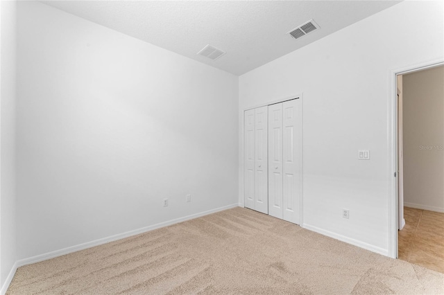 unfurnished bedroom featuring light colored carpet and a closet