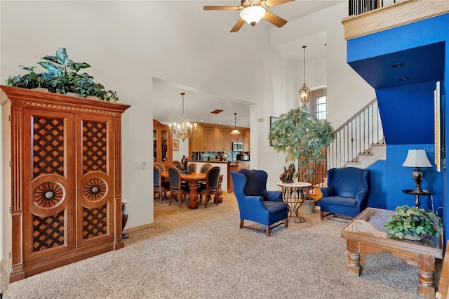 living room featuring carpet, a towering ceiling, and ceiling fan with notable chandelier