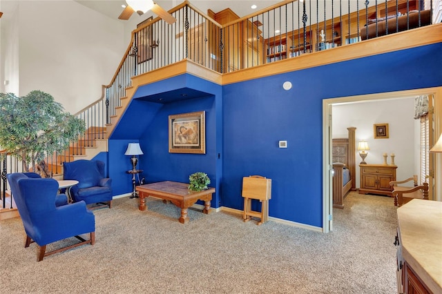 living room with carpet flooring, ceiling fan, and a towering ceiling