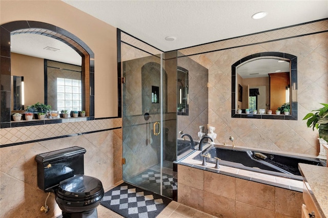 bathroom featuring plus walk in shower, vanity, tile patterned flooring, and tile walls