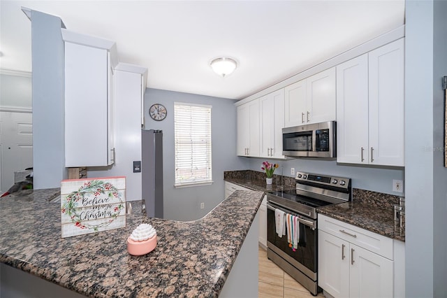 kitchen featuring dark stone countertops, kitchen peninsula, white cabinets, and appliances with stainless steel finishes