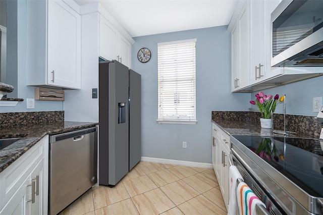 kitchen featuring white cabinets, light tile patterned floors, stainless steel appliances, and dark stone counters