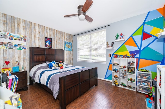 bedroom with wood walls, ceiling fan, and dark wood-type flooring