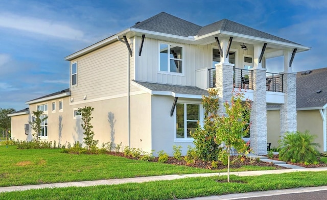 view of side of home with a balcony and a lawn