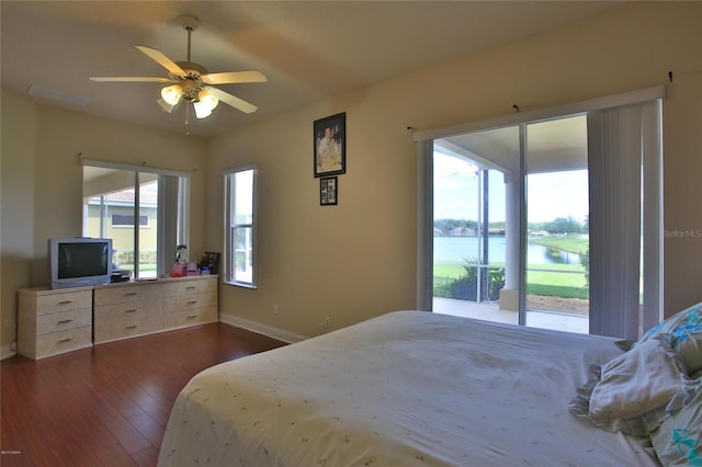 bedroom featuring access to exterior, ceiling fan, dark hardwood / wood-style flooring, and a water view