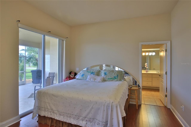 bedroom with hardwood / wood-style floors, access to outside, and connected bathroom