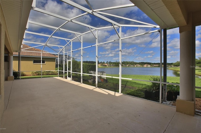 view of patio / terrace featuring glass enclosure and a water view