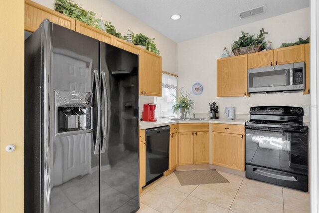 kitchen featuring black appliances, light brown cabinets, light tile patterned floors, and sink