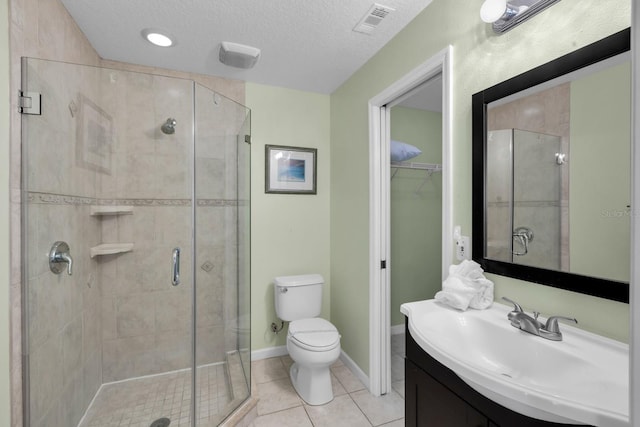 bathroom with tile patterned flooring, toilet, a shower with shower door, and a textured ceiling