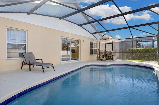 view of pool with glass enclosure and a patio