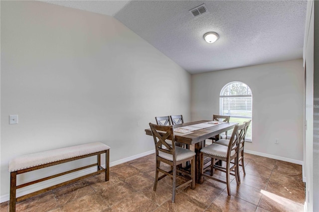 dining area featuring lofted ceiling and a textured ceiling