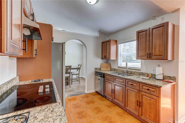 kitchen featuring a textured ceiling, sink, extractor fan, and stainless steel appliances