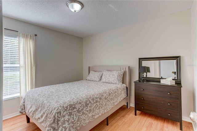 bedroom with light hardwood / wood-style floors and a textured ceiling