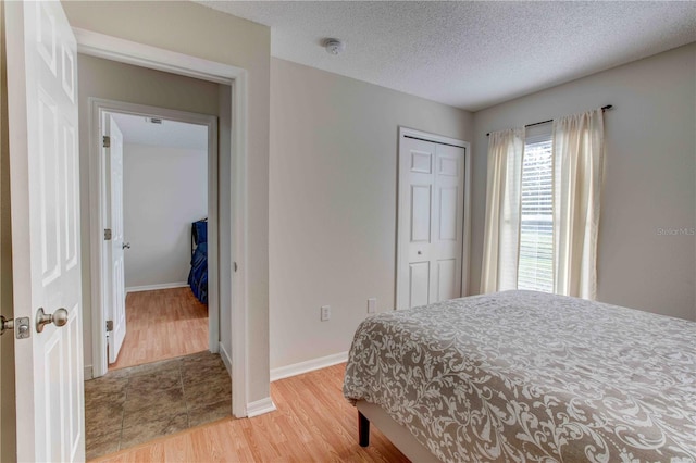 bedroom featuring a closet, wood-type flooring, and a textured ceiling