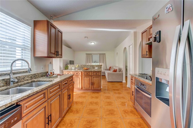 kitchen with light stone countertops, stainless steel appliances, vaulted ceiling, sink, and light tile patterned flooring