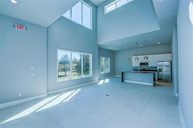 unfurnished living room featuring a high ceiling, light tile patterned floors, and sink