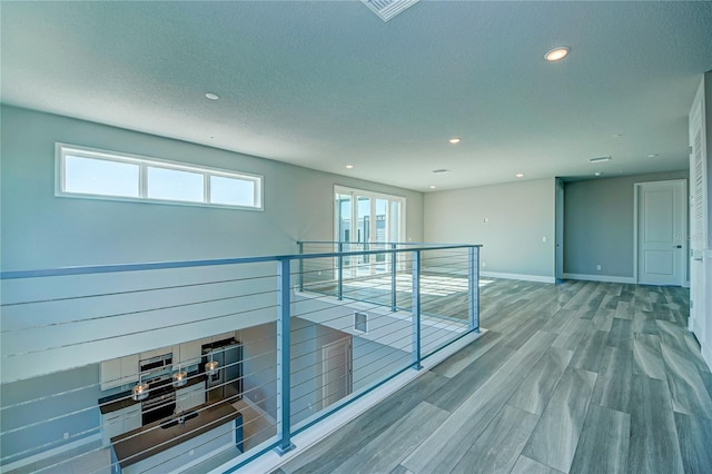 hallway with hardwood / wood-style floors and a textured ceiling