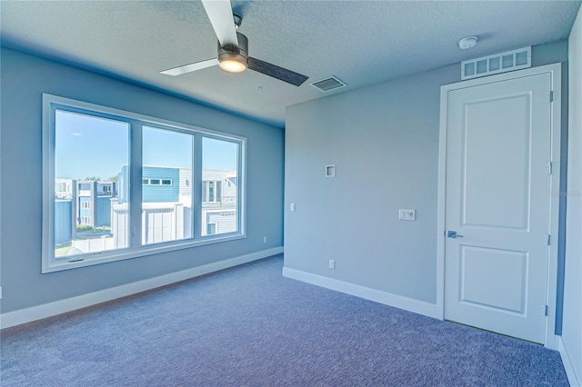 carpeted empty room featuring ceiling fan and a textured ceiling