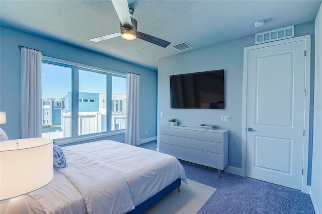 bedroom with ceiling fan, carpet, and a textured ceiling