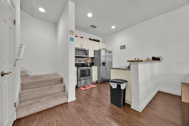 kitchen with kitchen peninsula, white cabinetry, dark wood-type flooring, and appliances with stainless steel finishes