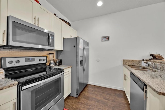 kitchen with dark wood-type flooring, light stone counters, sink, and stainless steel appliances