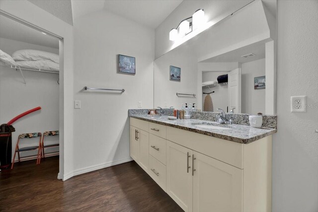 bathroom featuring vanity, wood-type flooring, and vaulted ceiling