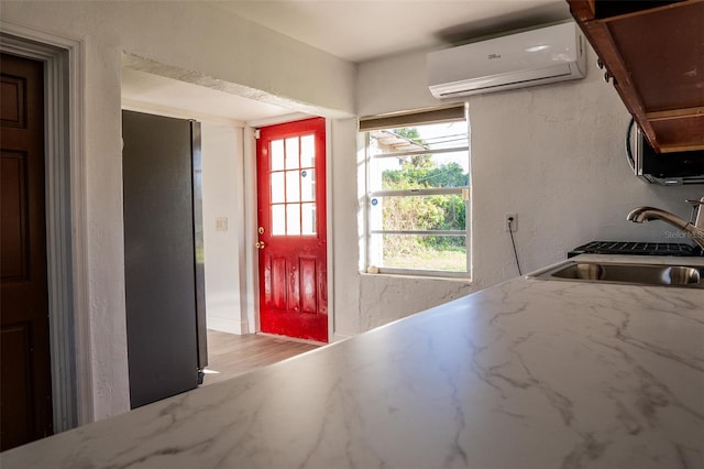 kitchen featuring an AC wall unit, sink, and light hardwood / wood-style flooring