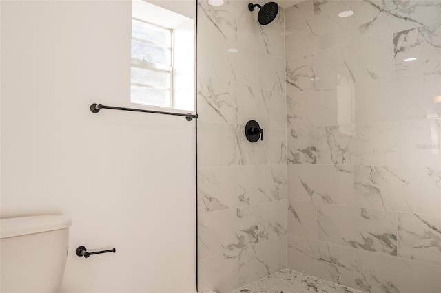 bathroom featuring a tile shower and toilet