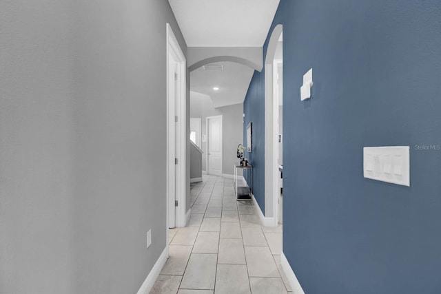 hallway with light tile patterned floors and vaulted ceiling