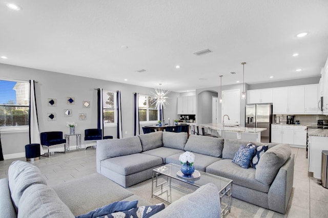 living room with sink, light tile patterned floors, and a notable chandelier