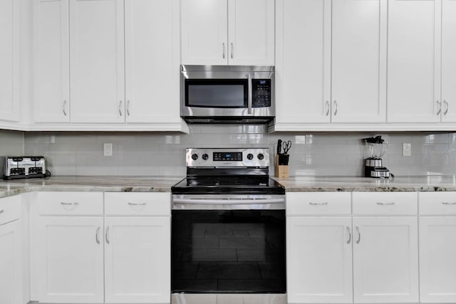 kitchen with tasteful backsplash, white cabinetry, light stone countertops, and appliances with stainless steel finishes