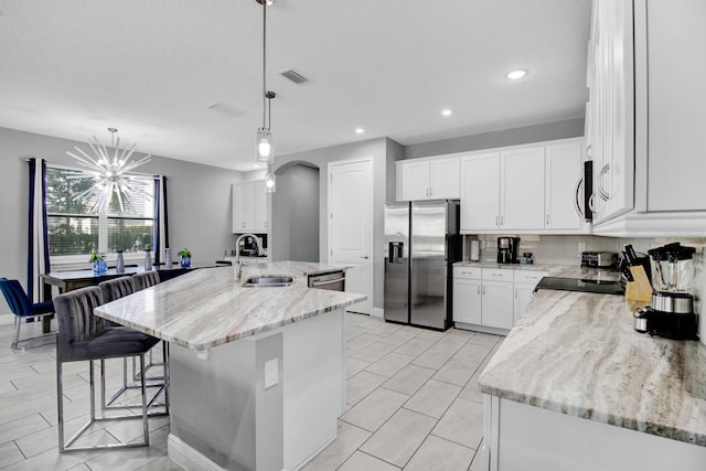 kitchen with sink, decorative light fixtures, a center island with sink, white cabinets, and appliances with stainless steel finishes