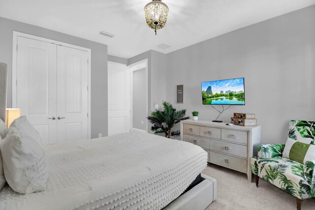 bedroom featuring a notable chandelier, light colored carpet, and a closet