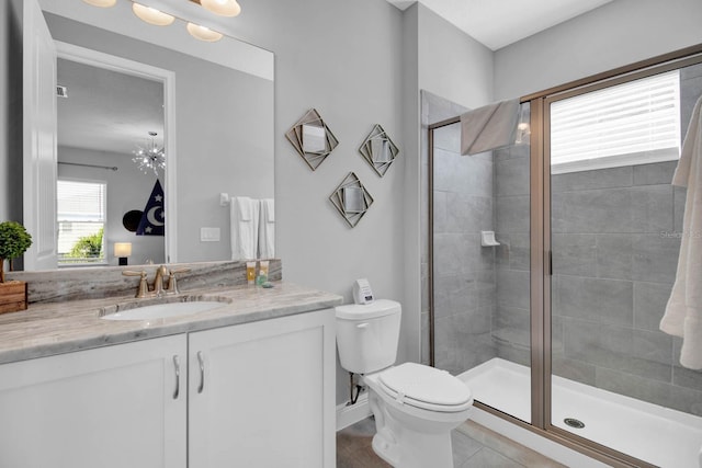 bathroom with an inviting chandelier, tile patterned flooring, toilet, a shower with door, and vanity