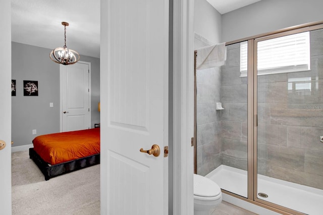 bathroom with toilet, a shower with shower door, and a chandelier