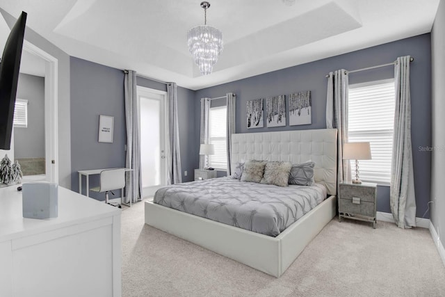 carpeted bedroom with a raised ceiling and an inviting chandelier