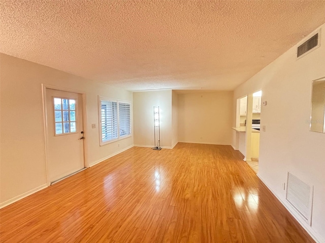 spare room with light hardwood / wood-style floors and a textured ceiling