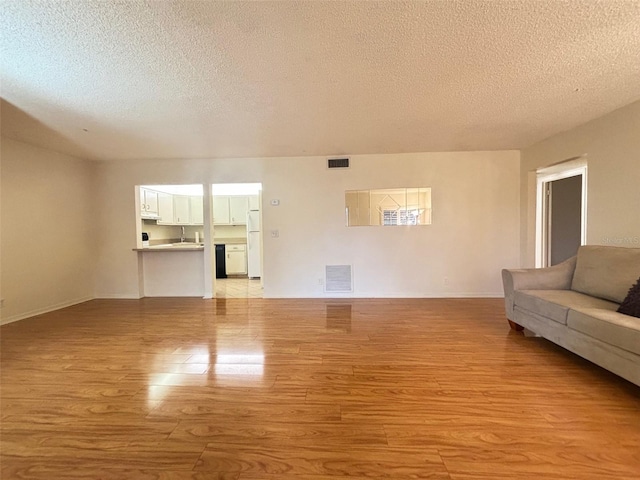 unfurnished living room with light hardwood / wood-style flooring, a textured ceiling, and sink