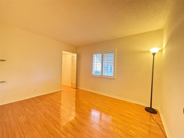 spare room featuring a textured ceiling and light hardwood / wood-style flooring