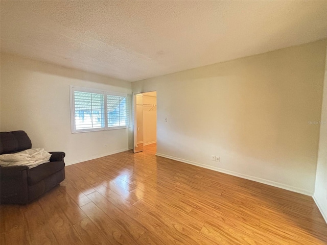 unfurnished room with light hardwood / wood-style floors and a textured ceiling