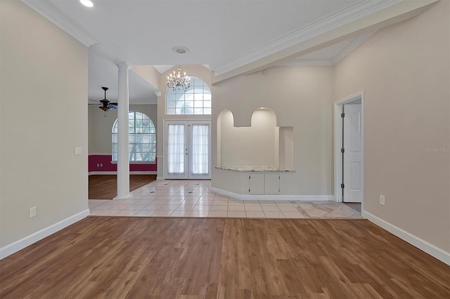 entrance foyer with light hardwood / wood-style flooring, decorative columns, ornamental molding, ceiling fan with notable chandelier, and french doors