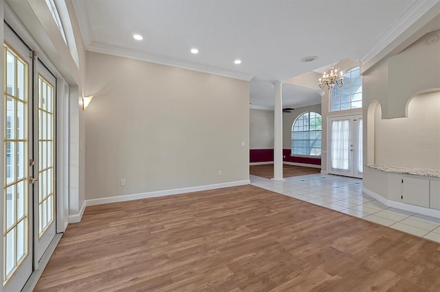 entrance foyer featuring an inviting chandelier, ornamental molding, french doors, and light wood-type flooring