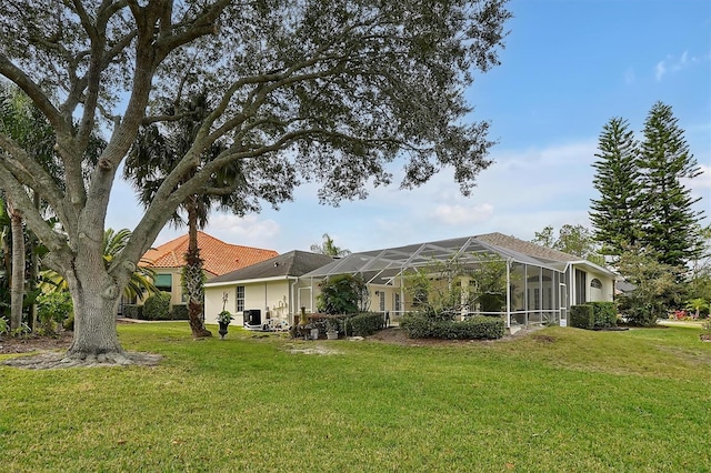 rear view of house featuring a yard and glass enclosure