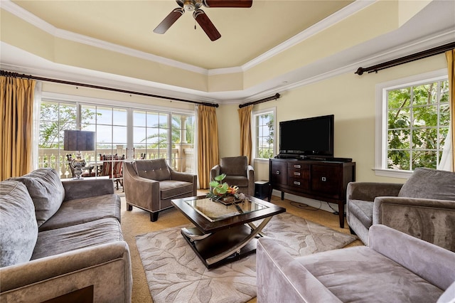 living room with a raised ceiling, ceiling fan, a healthy amount of sunlight, and ornamental molding