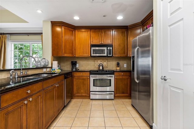 kitchen with dark stone counters, sink, decorative backsplash, light tile patterned floors, and stainless steel appliances