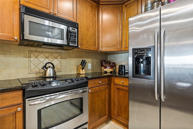 kitchen with decorative backsplash, light tile patterned flooring, dark stone countertops, and stainless steel appliances