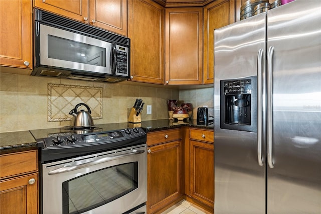 1370 Centre Court Ridge Dr Unit 304, Kissimmee, FL 34747 - kitchen with appliances with stainless steel finishes, brown cabinetry, dark stone counters, and decorative backsplash