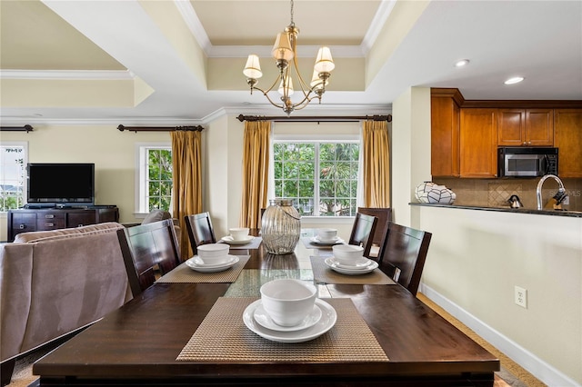 dining room with a raised ceiling, crown molding, and a wealth of natural light